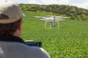UAV Drone Pilot Flying and Gathering Data Over Country Farm Land